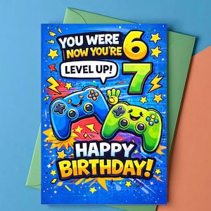 以下が含まれることがあります： 青い背景の誕生日カード。青と緑の2つのゲームコントローラーと、「You Were Now You're Level Up!」と「Happy Birthday!」のテキスト、数字の6と7が表示されています。