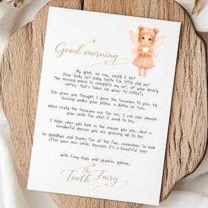 May include: A white card with the text "Good morning" and a poem about the Tooth Fairy. The card features a watercolor illustration of a fairy holding a heart. The card is on a wooden surface.