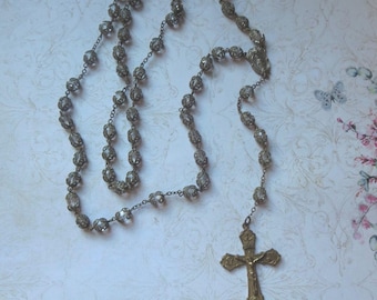 May include: Vintage rosary featuring clear, faceted beads and a detailed metal crucifix. The beads are strung on a delicate chain, and the cross has an image of Jesus. A religious item.