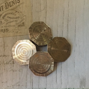 May include: Four silver-toned cufflinks with a circular, concentric design. The cufflinks are arranged in a cluster on a light gray surface.