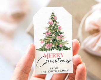 May include: A white Christmas gift tag with a watercolor illustration of a green Christmas tree decorated with pink bows and ornaments. The tag reads "MERRY Christmas" and "FROM, THE SMITH FAMILY" in black script.