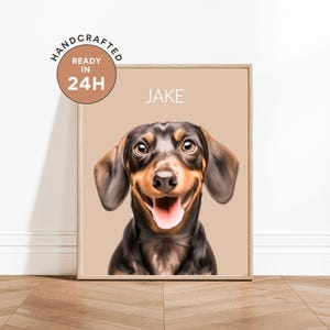Puede incluir: Retrato enmarcado de un perro salchicha sonriente llamado Jake. El perro tiene pelaje negro y marrón, con una lengua rosada. El fondo es de color marrón claro. El marco es de color madera clara. El texto "Handcrafted Ready in 24H" está en un círculo en la esquina superior izquierda.
