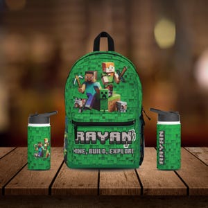 May include: Green Minecraft backpack with a character from the game on the front. The backpack has the name "Rayan" and the words "Mine, Build, Explore" on it. The set also includes two green water bottles with the name "Rayan" on them.
