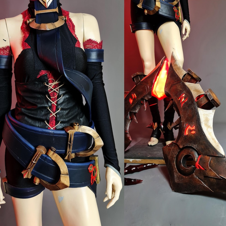 May include: A cosplay costume featuring a black top with red lacing and accents, paired with black shorts and a blue belt with gold-colored details. The costume includes a large, ornate brown and red leg armor piece with glowing accents.