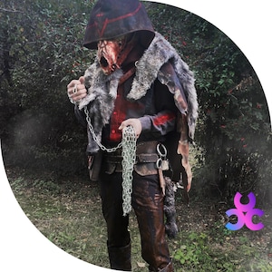 May include: A person wearing a hooded costume with a mask, fur trim, and a chain. The costume is red, brown, and white. The person is holding the chain in their hand.