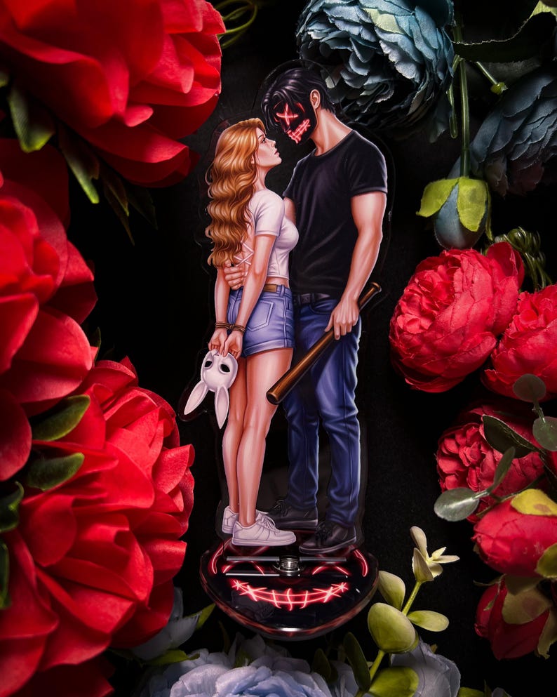 May include: A decorative acrylic figure featuring a couple embracing, with a red X mask and a bunny mask. The man holds a baseball bat. The base is heart-shaped with a red glowing smile design. Surrounded by red and blue flowers.