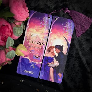 Puede incluir: Dos marcadores de color degradado morado y rosa con una escena romántica de una pareja en un entorno de fantasía. El texto en el marcador dice "VILARIS NESTA & CASSIAN".