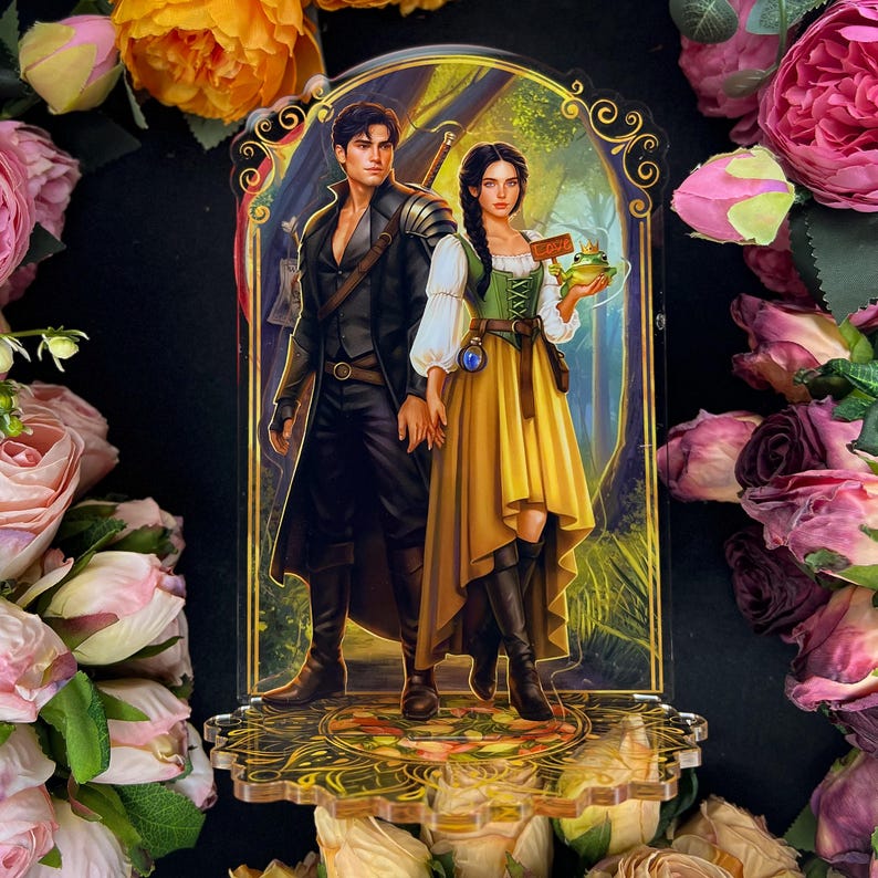 Pu&ograve; includere: Supporto in acrilico raffigurante una coppia fantasy. L'uomo indossa un cappotto nero e una spada. La donna indossa un corsetto verde, una gonna gialla e tiene in mano una rana. Lo sfondo &egrave; una scena di foresta con dettagli dorati.