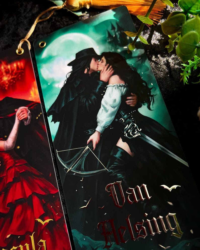 May include: Bookmarks featuring illustrations of characters from a gothic romance. One bookmark depicts a couple kissing in front of a full moon, with the words "Van Helsing" in red. The other bookmark shows a woman in a red dress.