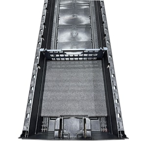 May include: A long, black, rectangular plastic storage tray featuring a series of moulded compartments along the sides, a removable grid-style divider, and a flat, textured grey foam insert lining the base of the central storage section.