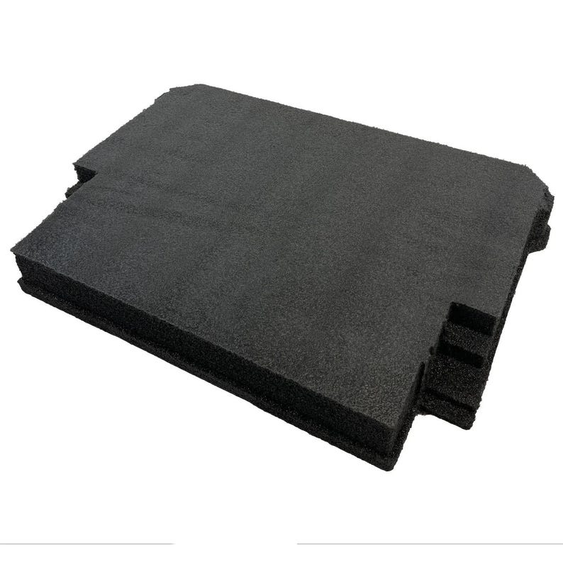 May include: A rectangular black foam insert with a textured, porous surface. The piece features specific cutouts along the edges, including a stepped section on one side and a notched corner, designed for protective storage or organisational purposes.