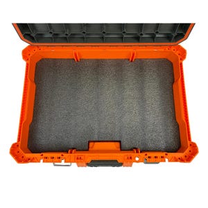May include: An open rectangular storage case featuring a bright orange exterior frame and a dark grey interior lining. The case includes a thick, textured dark grey foam insert that covers the entire base, providing a cushioned storage area.