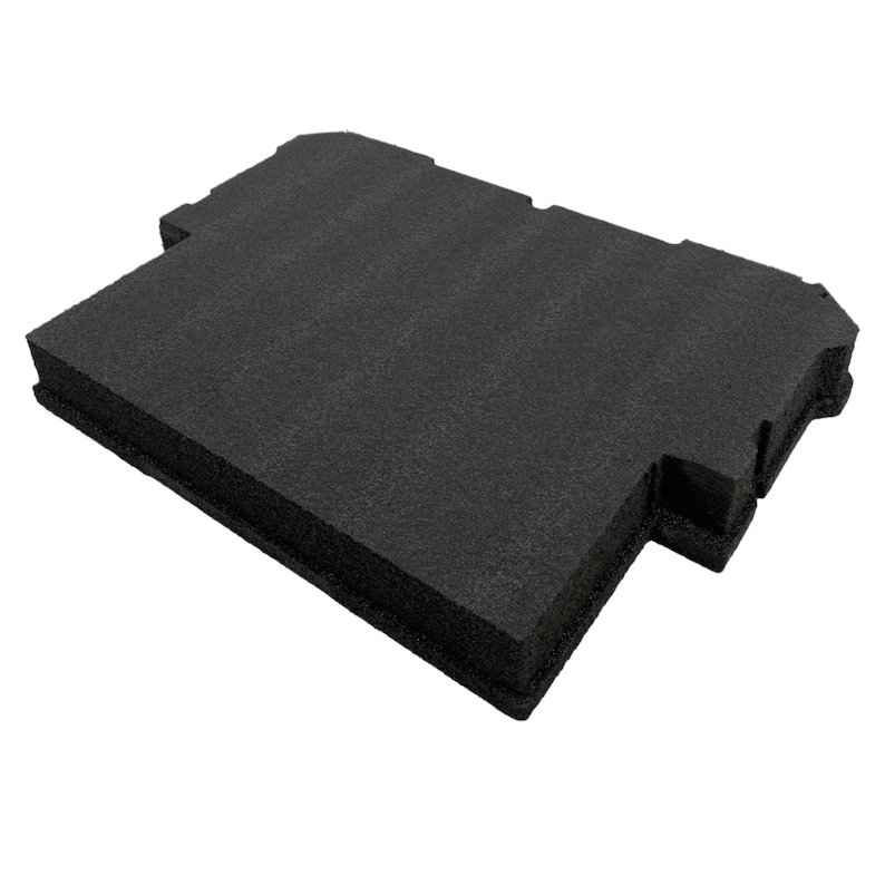 May include: A rectangular black foam insert with a textured surface and specific cutouts along the edges. The object features a flat top and a thick, dense structure, designed with precise notches and indentations on the sides for a custom fit.