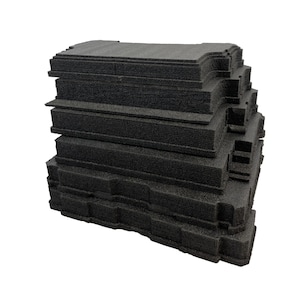 May include: A stack of rectangular black foam inserts with textured surfaces and notched edges. Each piece features a consistent layered design with precise cutouts along the sides, arranged vertically to form a uniform block of protective material.