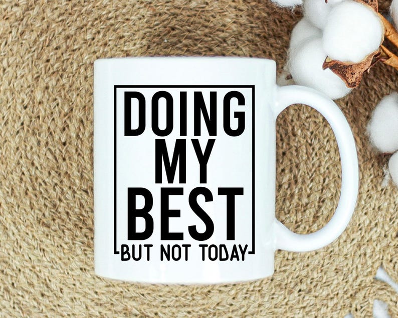 May include: White ceramic mug with the text "DOING MY BEST BUT NOT TODAY" in black, within a black rectangular border. The mug has a curved handle and is set against a neutral background.