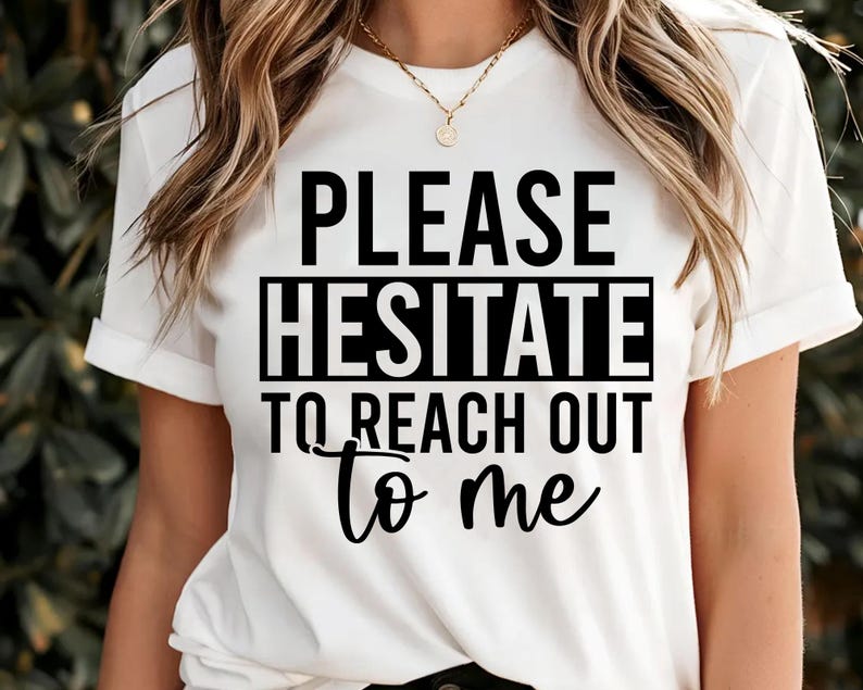 May include: White t-shirt with the text "PLEASE HESITATE TO REACH OUT to me" in black. The shirt has short sleeves and a crew neck. The text is centered on the front of the shirt.