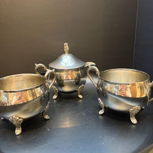 Puede incluir: Un juego de tres tazas de cerámica con un acabado mate moteado. Las tazas son de color crema, gris claro y gris oscuro. Cada taza tiene un diseño simple y minimalista.