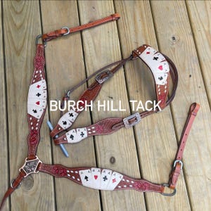 May include: A brown leather horse tack set with playing card designs. The set includes a headstall, breast collar, and reins. The playing card suits are red hearts and diamonds, and black spades and clubs. The text "BURCH HILL TACK" is visible.