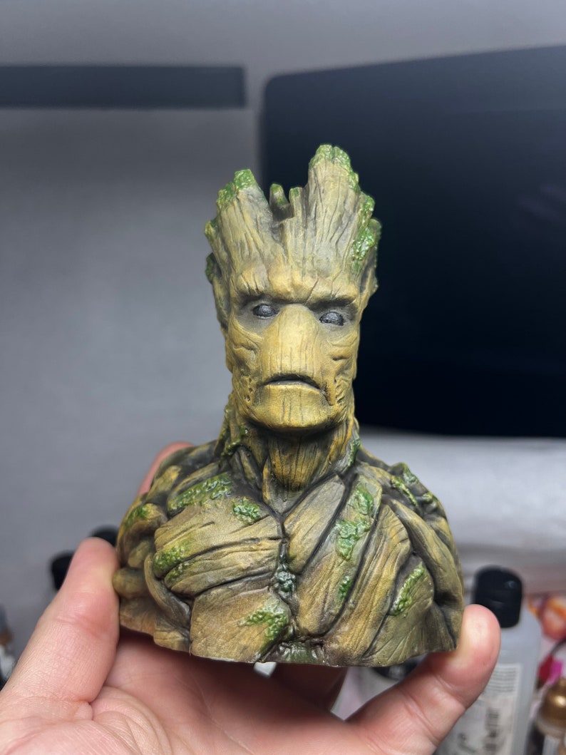 K&ouml;nnte beinhalten: Eine gr&uuml;ne und braune Figur von Groot aus Guardians of the Galaxy. Die Figur ist ein B&uuml;ste von Groots Kopf und Schultern, mit einer detaillierten Textur aus Rinde und Bl&auml;ttern.