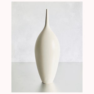 May include: A white ceramic vase with a tall, slender neck and a rounded body.