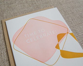 May include: A white card with a pink and gold abstract design. The text "TIME TO CELEBRATE!" is printed in white on the card.