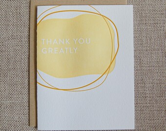 May include: A white card with a yellow abstract shape and gold circles around it. The text "THANK YOU GREATLY" is printed in white on the yellow shape.