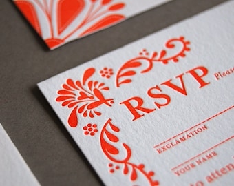 以下が含まれることがあります： 赤い花柄のデザインと大きな赤い文字で「RSVP」と書かれた白いRSVPカード。 「記入してください」というテキストも赤い文字で書かれています。 カードには、ゲストが自分の名前と出席するかどうかを記入するための線が引かれています。