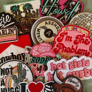 May include: A collection of colorful embroidered iron-on patches featuring various designs, including a cowboy hat, a cactus, a bull, a disco ball, and the text "I'm the problem".