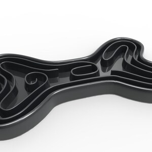 May include: Black bone-shaped slow feeder dog bowl with a maze design. The bowl has multiple ridges and curves to slow down eating.