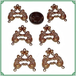 May include: Six identical copper-toned metal filigree connectors with ornate scrollwork patterns, each featuring three small loops for attachment. A United States dime is positioned in the center for scale, measuring approximately 0.705 inches in diameter.