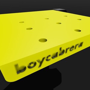 May include: A yellow, square-shaped workbench with multiple holes and the text "boycabretu" printed on the surface.