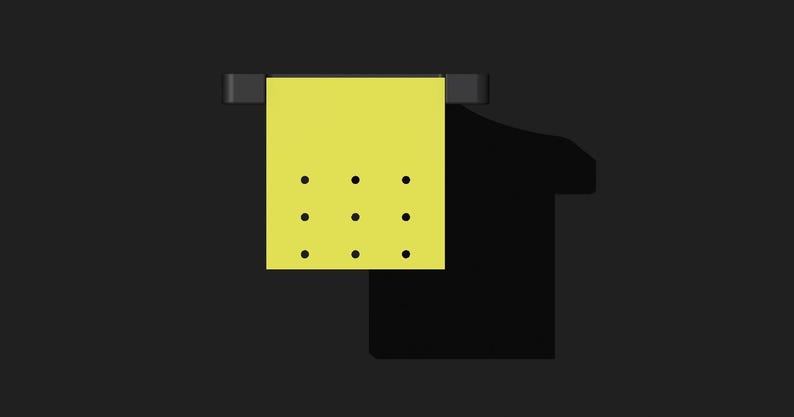 May include: A yellow sticky note with nine black dots hanging on a black hook.