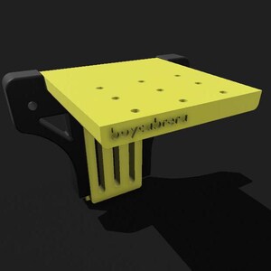 May include: A yellow plastic workbench with a black base and a label that says "boyabrend". The workbench has several holes drilled into the top surface.