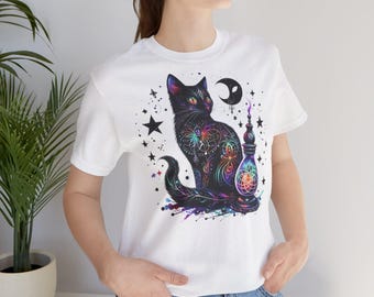 May include: White t-shirt featuring a black cat illustration adorned with a colourful, psychedelic design. The cat is sitting beside a bottle with a crescent moon above it.