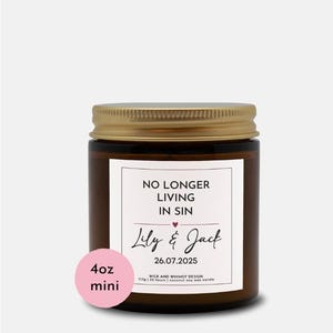 Könnte beinhalten: Ein braunes Glas-Kerzenglas mit goldenem Deckel. Das Etikett lautet "NO LONGER LIVING IN SIN" mit den Namen "Lily & Jack" und dem Datum "26.07.2025". Ein rosa Aufkleber zeigt eine Mini-Kerze von 113g an.