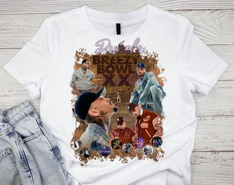 May include: White t-shirt featuring a graphic design with the text "Purple Breezy Bowl XX Creations". The design includes images of a person in various poses, with colorful orbs at the bottom. The shirt is paired with light wash denim jeans.