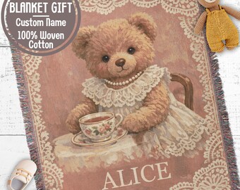 May include: A woven cotton blanket featuring a teddy bear wearing a lace collar and pearls, holding a floral teacup. The blanket has a dusty rose background with a white lace border and the name ALICE printed in white. Text reads BABY BLANKET GIFT.