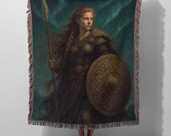May include: A woven throw blanket featuring a detailed illustration of a warrior with long red hair, wearing dark armor, holding a tall spear in one hand and a round wooden shield with intricate Celtic knotwork patterns in the other hand.