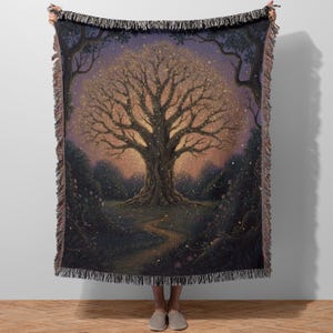 Puede incluir: Una manta tejida con una ilustración detallada de un gran árbol con hojas brillantes en un entorno forestal. La obra de arte tiene una paleta de colores cálidos con un camino que conduce al árbol. La manta tiene un borde con flecos.