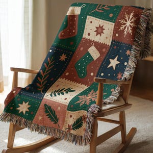 Puede incluir: Una manta decorativa con temática navideña, sobre una mecedora de madera. La manta presenta un diseño de patchwork con cuadrados verdes, marrones y crema, adornados con motivos festivos como calcetines, estrellas y copos de nieve. La manta tiene un borde con flecos.