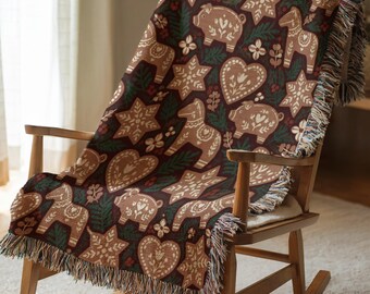 May include: A woven throw blanket featuring a dark brown background with a repeating pattern of light brown gingerbread-style pigs, horses, hearts, and stars, accented by green pine sprigs and finished with a fringed edge.