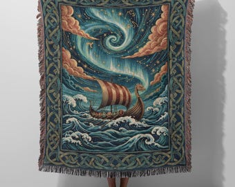May include: A woven throw blanket featuring a Viking longship sailing through turbulent blue ocean waves under a swirling night sky with stars, constellations, and pink clouds, framed by a dark blue border with an intricate Celtic knot pattern.