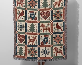 May include: A woven throw blanket featuring a grid pattern of holiday-themed icons including red cardinals, green pine trees, reindeer, Dala horses, stockings, hearts, snowflakes, and geometric stars in shades of red, green, blue, and cream.