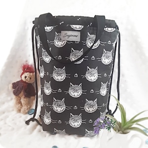 May include: Black drawstring bag with a white grinning cat pattern and the text "Sugirons" on the front.