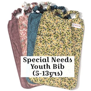 May include: A collection of five youth bibs with various fabric patterns, including floral and paisley designs. The bibs have a loop at the top and are labeled "Special Needs Youth Bib (5-13yrs)".