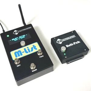 May include: A black foot pedal with the text "TC AUTOMATION" and "M-List" in white. The pedal has four buttons labeled "REV", "MAIN", "FWD", and a knob. A smaller black box with the text "TC AUTOMATION" and "Belt-Pak" in white is also shown.