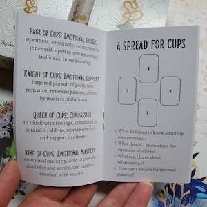May include: A white booklet with a black and white spread for cups tarot card reading. The booklet includes descriptions of the meaning of each card in the spread. The spread includes four cards numbered 1 through 4. The text on the booklet reads "A Spread for Cups".