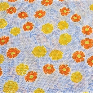 May include: A white fabric with a repeating pattern of orange and yellow flowers. The flowers are stylized and have a simple design.