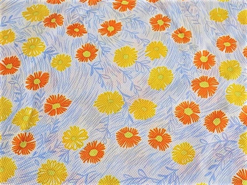 May include: A white fabric with a repeating pattern of orange and yellow flowers. The flowers are stylized and have a simple design.
