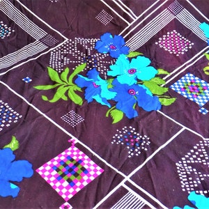 May include: A dark brown fabric with a geometric pattern of white and black lines, white and black squares, and white and black dots. The fabric also features a floral pattern with blue, green, and purple flowers.